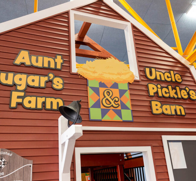 Sign outside farm exhibit. Text reads, "Aunt Sugar's Farm and Uncle Pickle's Barn."